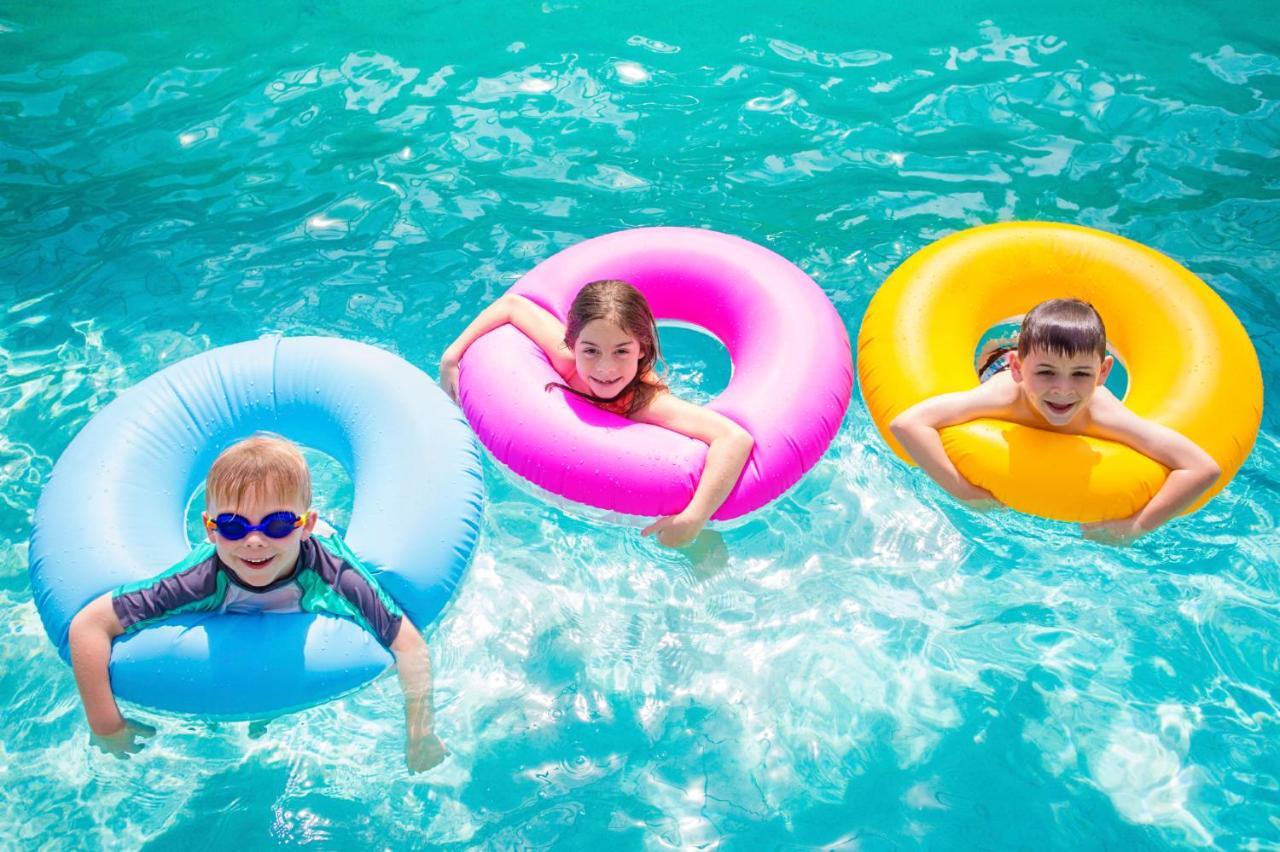 The Act Hotel Sharjah Exterior photo Children using inner tubes in a swimming pool